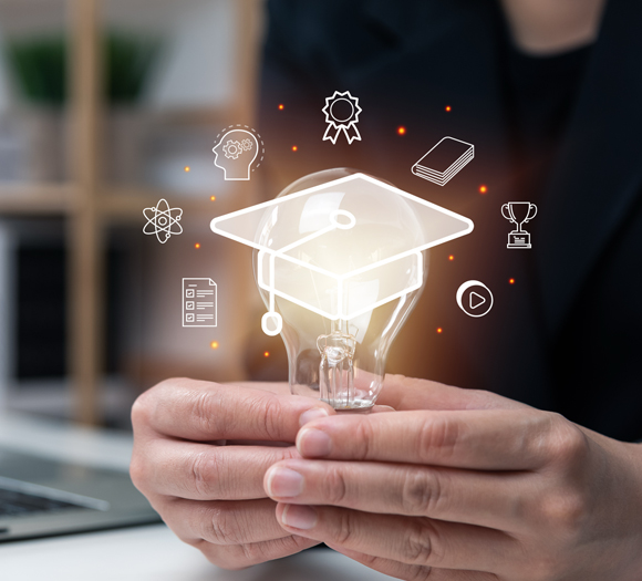 A person holds a glowing light bulb in both hands. Above it, a graduation cap is illustrated, surrounded by icons of a trophy, book, and certificate, symbolizing education and achievement.